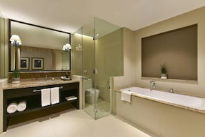A modern bathroom with a glass-enclosed shower, a large mirror, a double sink vanity, and a potted plant.