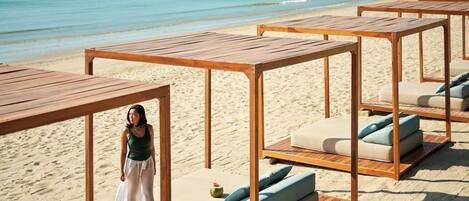 Un resort frente a la playa con cabañas de madera y asientos acolchados.