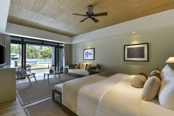 A hotel room with a large bed, a desk, a chair, a sofa, and a ceiling fan. - Seda Lio El Nido Palawan (El Nido)