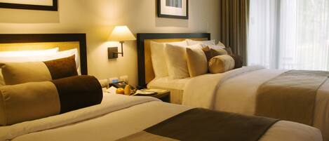 A hotel room with two beds, a nightstand with a lamp, and a window with curtains.
