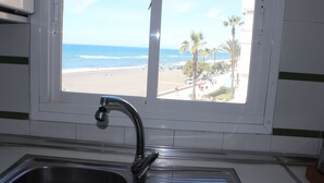 A kitchen with a window overlooking a beach. - Fantastic oceanfront apartment (Torrox Costa)