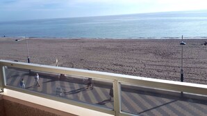 A beach view from a balcony with a railing, a clear sky, and the ocean in the background. - Fantastic oceanfront apartment (Torrox Costa)