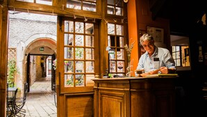 Una zona de bar con mostrador de madera, un ventanal con vista a la calle y una puerta que da a un espacio exterior.