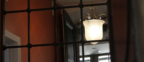 A hallway with a geometric metal railing and a hanging light fixture.