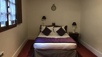 Une chambre à coucher avec un lit, deux tables de chevet avec des lampes, une fenêtre avec des rideaux et un anneau lumineux fixé au mur.