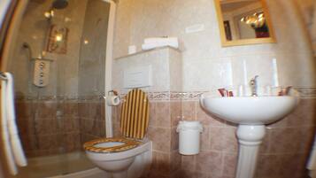Et badeværelse med brusebad, toilet, vask og spejl.
