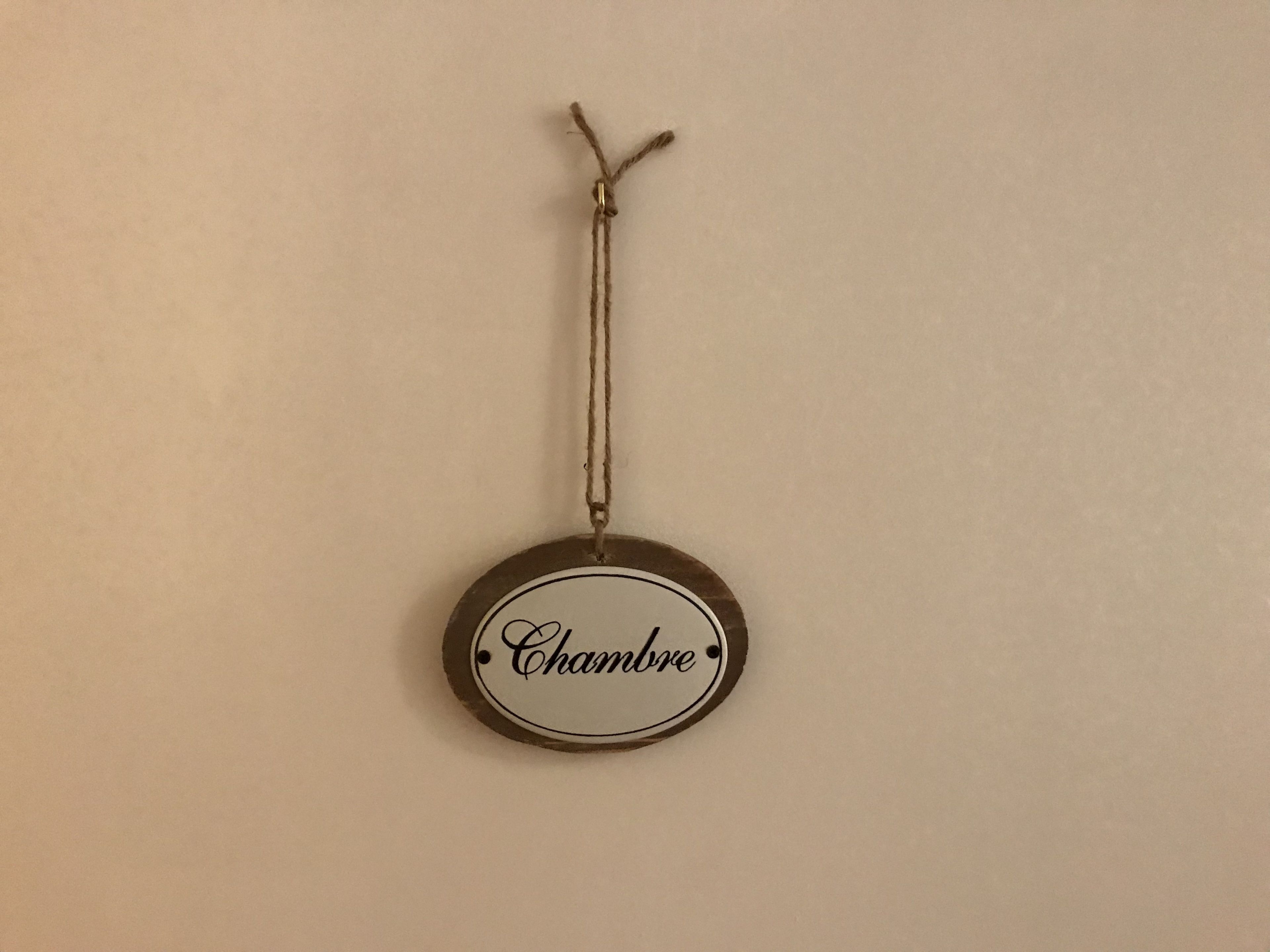 A circular sign with the word "Chambre" hanging on a wall.