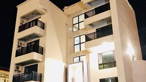 A multi-story building with balconies, a central entrance, and outdoor seating. - Longman Villa (Huxi)