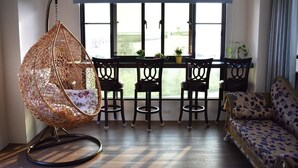 A room with a hanging chair, a sofa, a dining table with chairs, and a view through large windows. - Longman Villa (Huxi)