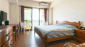 A bedroom with a wooden bed, a bedside table, a dresser, a TV, and a balcony with a chair. - Longman Villa (Huxi)