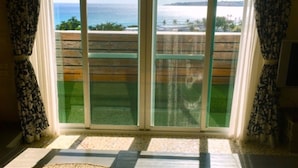 A room with a large sliding glass door leading to a balcony with a view of the ocean. - Daban Six Guest House (Hengchun)