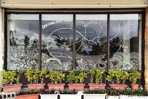 A storefront with a large window displaying intricate glass art and potted plants in front. - Daban Six Guest House (Hengchun)