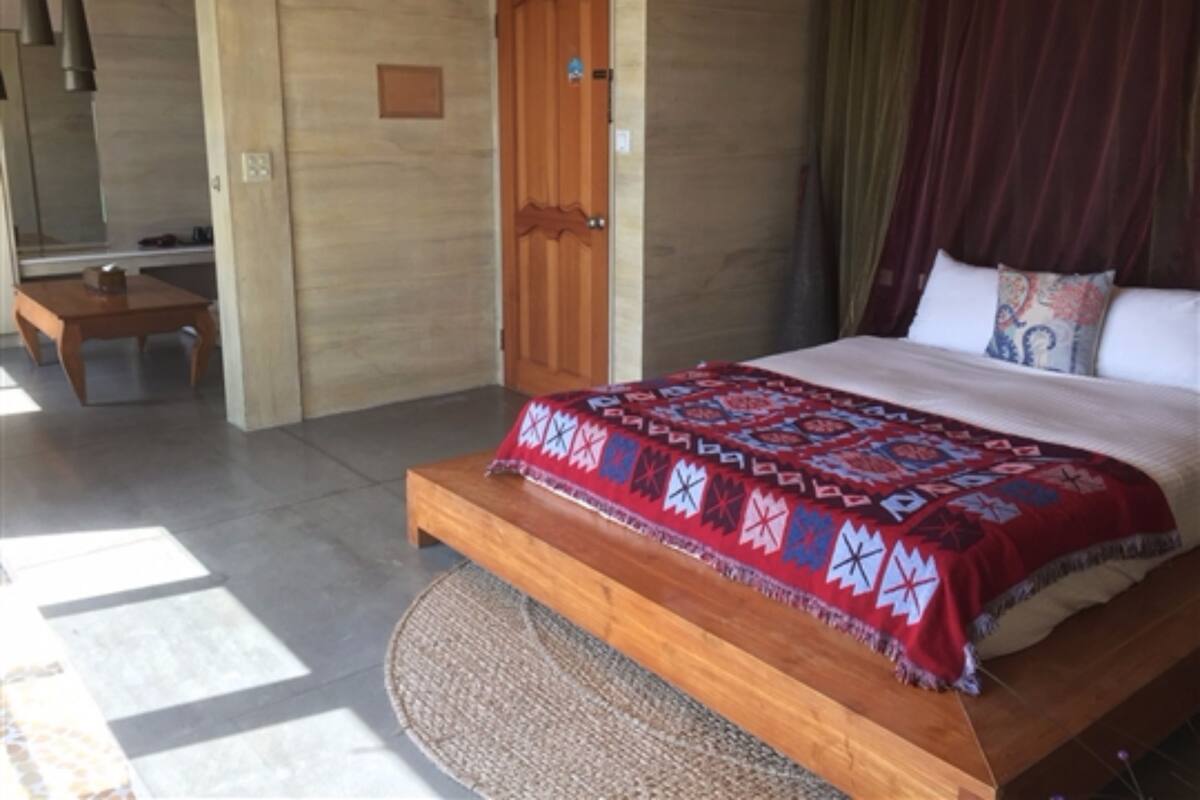 A bedroom with a wooden bed, a wooden nightstand, a mirror, and a door.