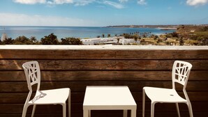 A terrace with two white chairs and a table, overlooking a coastal landscape with buildings and palm trees. - Daban Six Guest House (Hengchun)