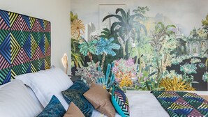 A bedroom with a bed, pillows, and a large mural of a cityscape and tropical plants. - Maison du Collectionneur (Aix-en-Provence)