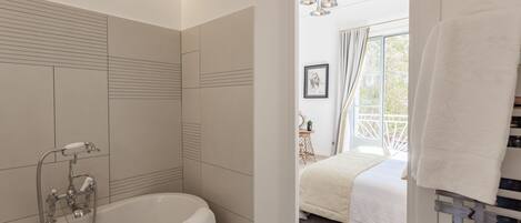 A modern bathroom with a freestanding bathtub, a shower with a handheld showerhead, and a towel rack.