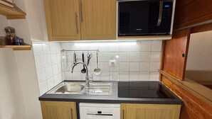 Una cucina compatta con mobili in legno, un forno a microonde, una lavastoviglie e un lavandino.