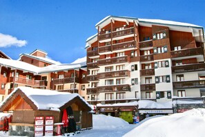 Een hotel met meerdere verdiepingen, balkons en een met sneeuw bedekte sneeuwkap.