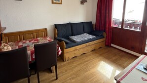 Una camera accogliente con un divano di legno, un tavolino con sedie e un letto con copriletto decorato.