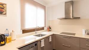Una cocina moderna con lavavajillas, pileta y campana extractora de acero inoxidable.