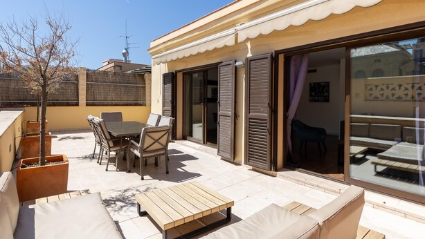 Una terraza en la azotea con una mesa de comedor, sillas, un banco de madera y un sofá.