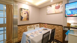 A dining area with a table set for two, a television mounted on the wall, and artwork on the walls. - 85 Asia Hotel (Kaohsiung)