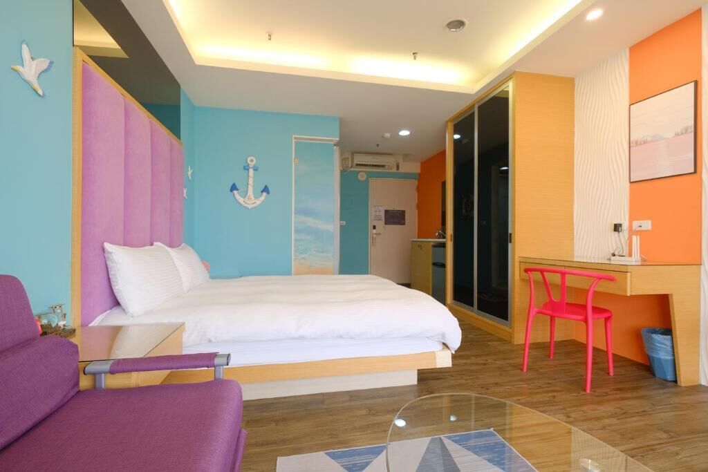A modern hotel room with a bed, a desk, and a chair.