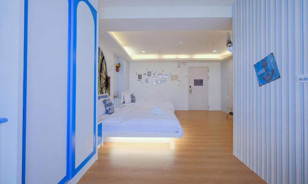 Een slaapkamer met een bed, een nachtkastje en een muur met ingelijste foto’s.
