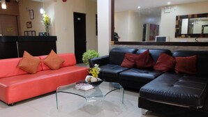 Una sala de estar moderna con un sofá rojo, un sofá negro y una mesa de centro de vidrio.