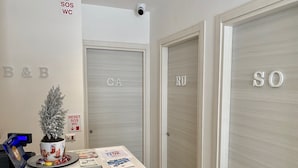 A reception area with a desk, a potted plant, and three doors labeled B&B, CA, and SO. - BeB Caruso (Sorrento)