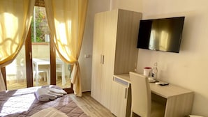 A hotel room with a bed, a desk, a TV, and a view of the outdoors. - BeB Caruso (Sorrento)
