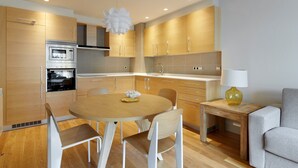 Una cocina moderna con armarios de madera, horno empotrado y una mesa redonda con sillas.