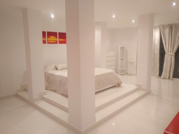 Ein modernes Schlafzimmer mit Bett, begehbarem Kleiderschrank und einem Badezimmer mit Dusche und Toilette.