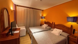 A hotel room with two beds, a desk, a chair, a dresser, and a window with curtains. - Hotel Rural Tierra de Lobos (Puebla de Sanabria)