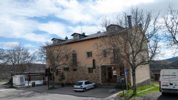A stone building with a flat roof and a car parked in front.