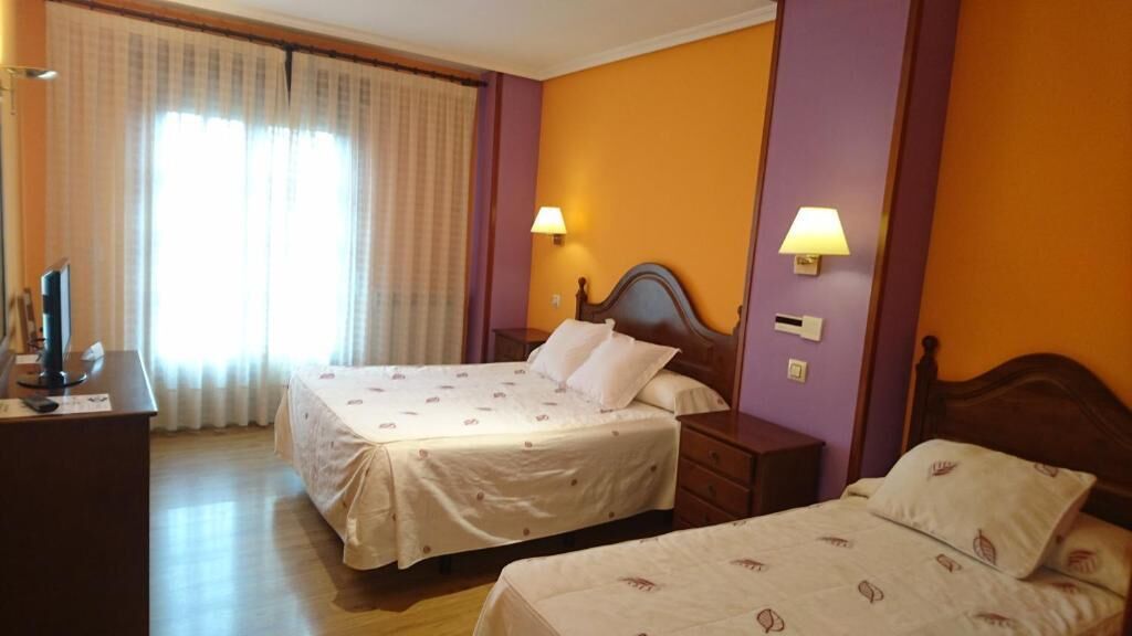 Ein Hotelzimmer mit zwei Betten, einem Schreibtisch und einem Fernseher.