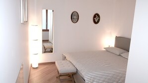 A bedroom with a bed, a bench, a mirror, and two wall decorations.