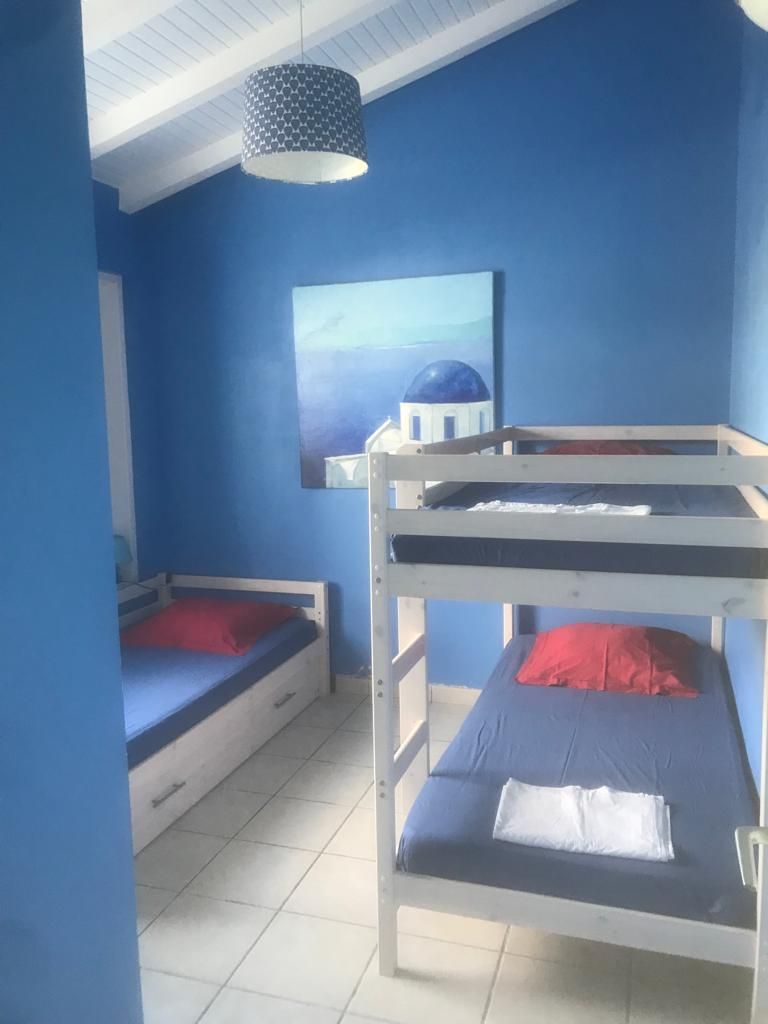 A room with two bunk beds, a blue wall, a ceiling light, and a painting of a dome structure.