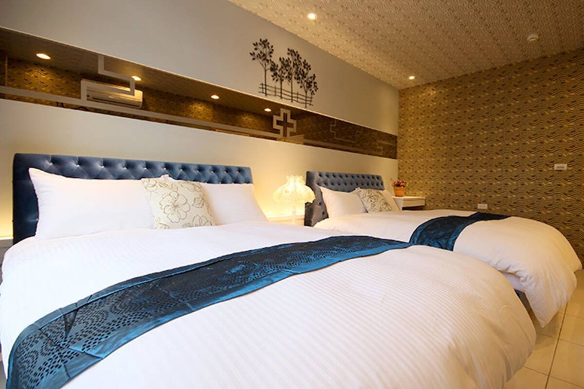 A large bed with a tufted headboard, white bedding, and a blue accent.