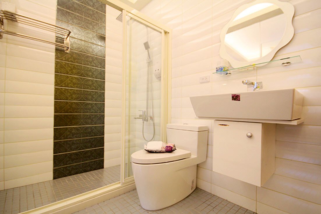 A bathroom with a toilet, shower, and a mirror above the sink.