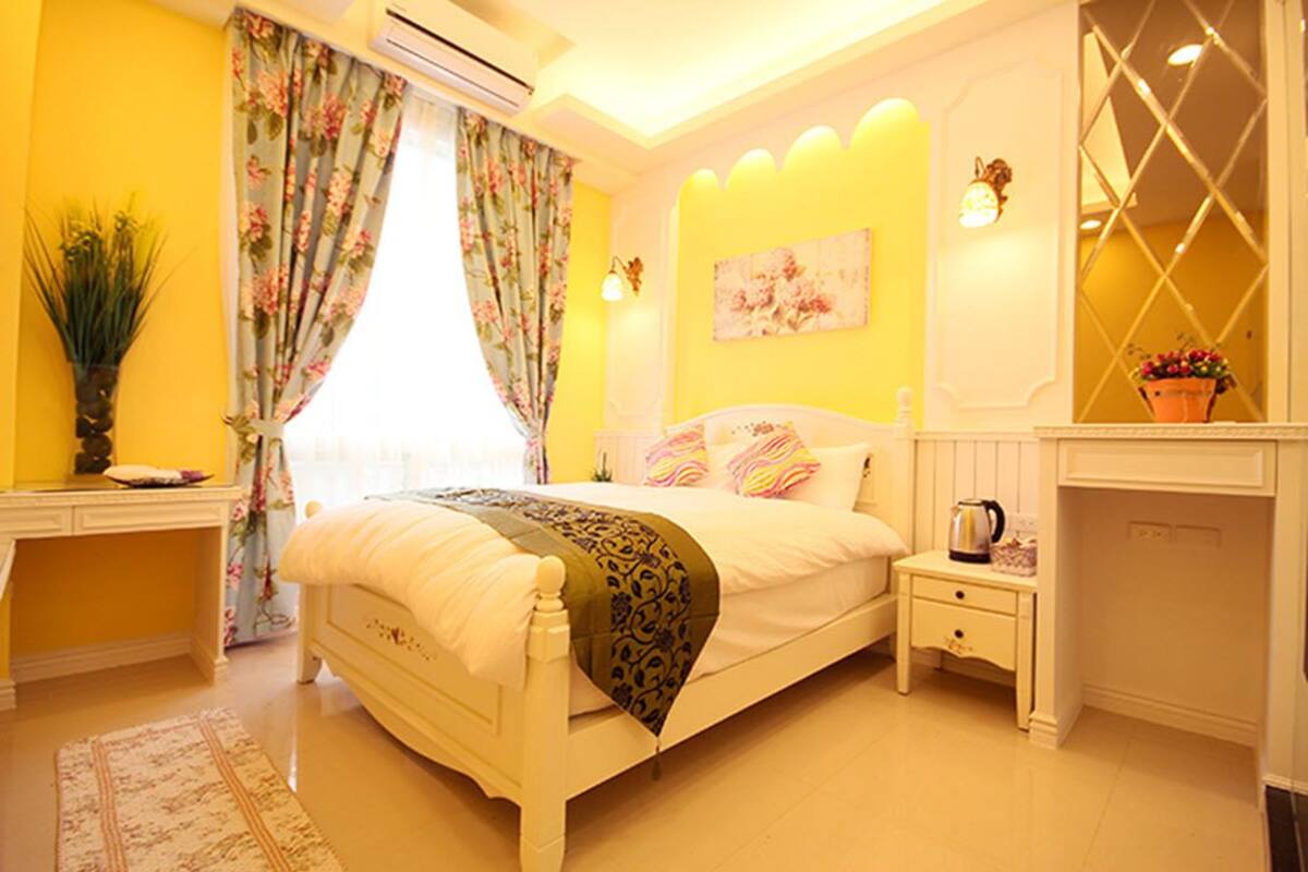 A bedroom with a bed, nightstand, and a window with curtains.