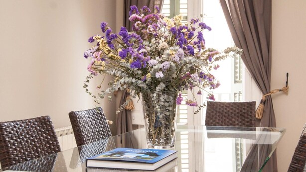 Een tafel met glazen blad, een boek en een bloevas.