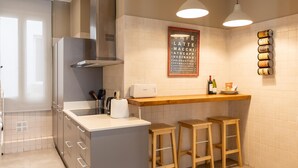 Een moderne keuken met een centraal eiland, een paar barkrukken, een koffieapparaat en een menubord.