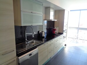 A modern kitchen with a stainless steel sink, a coffee machine, and wooden cabinets.