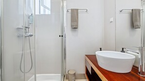 A modern bathroom with a glass-enclosed shower, a white sink, and a wooden vanity. - Hillside - By Wehost (Funchal)