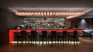 A modern bar area with a red-lit bar counter, multiple shelves of bottles, and several bar stools. - Onovo (Kyiv)