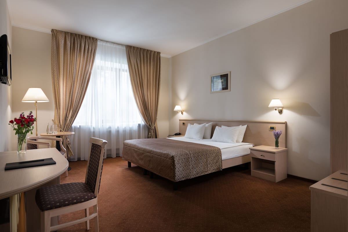 Una camera d'albergo con un letto, comodini, una scrivania e una sedia.
