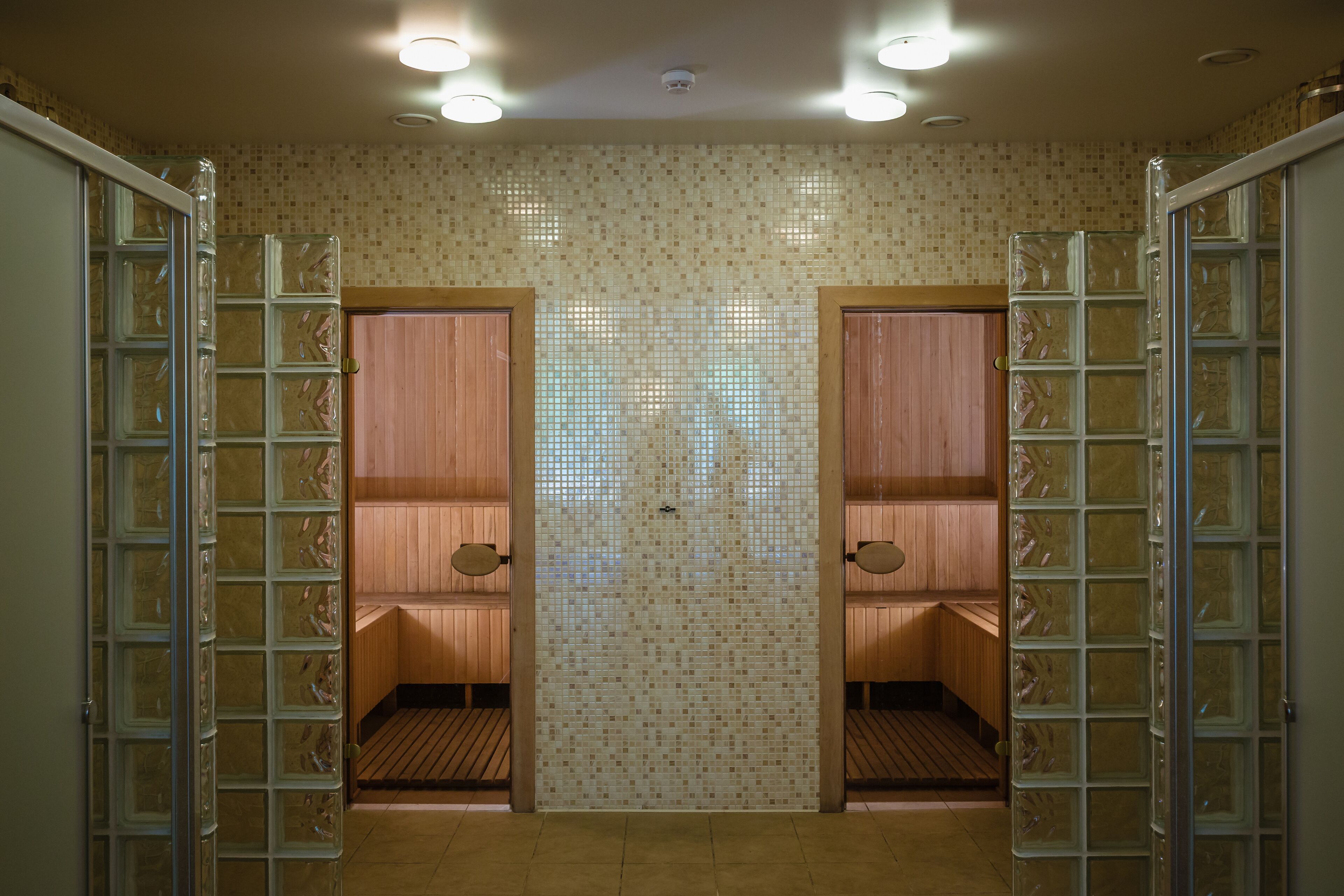 A sauna room with two wooden benches and glass partitions.