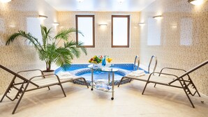 A spa room with a hot tub, two lounge chairs, a table with a plant and fruit, and a potted palm tree. - Onovo (Kyiv)