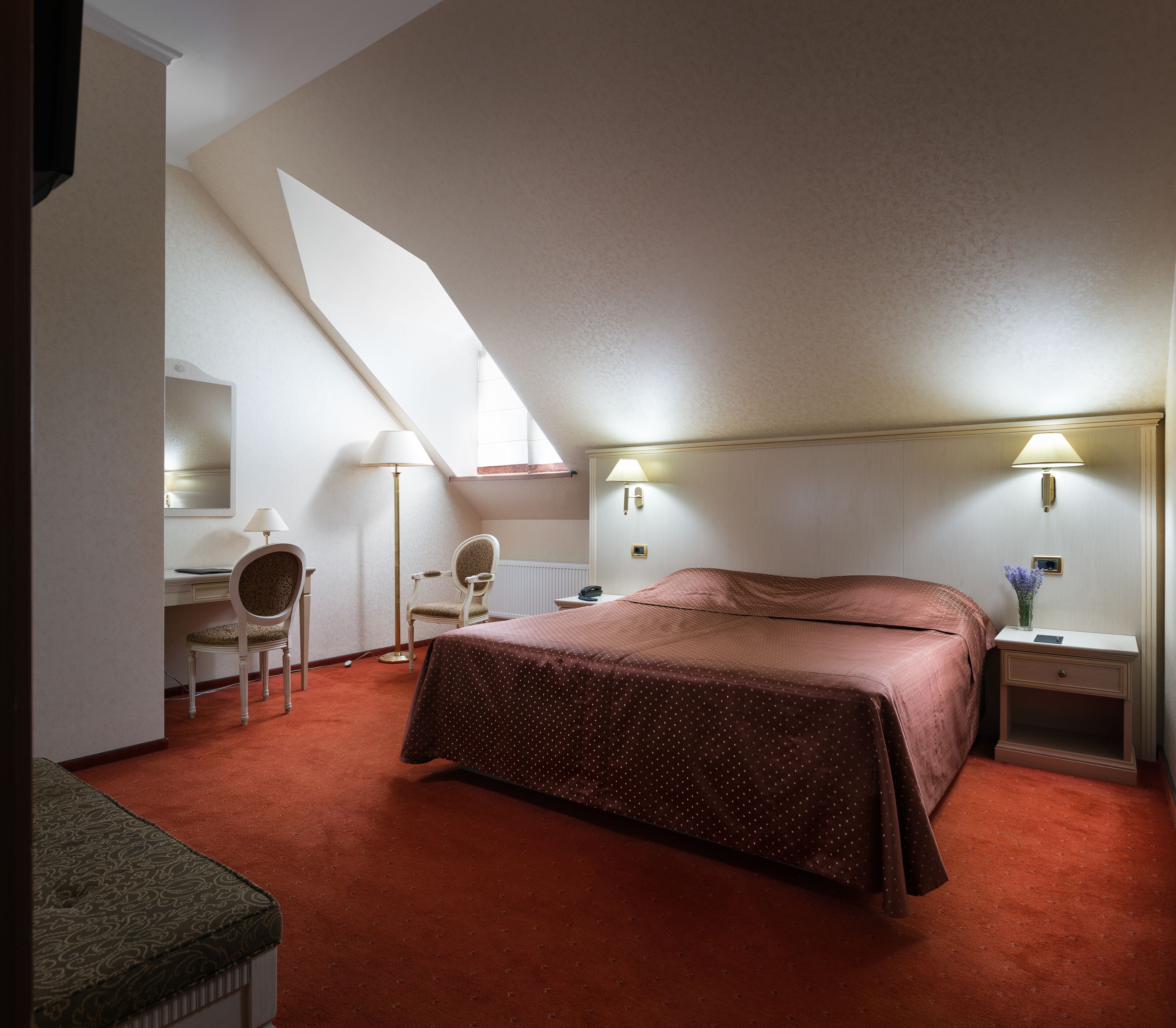 Ein Schlafzimmer mit einem großen Bett, einem Schreibtisch, einem Sessel und einem Nachttisch.